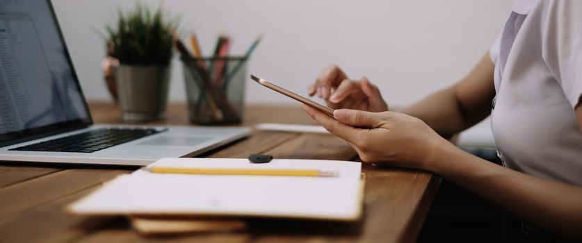 Young woman using digital tablet and computer for studying or working online at home.