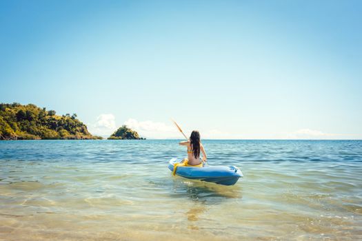Woman paddling on a kayak on sea in clear water enjoying the summer