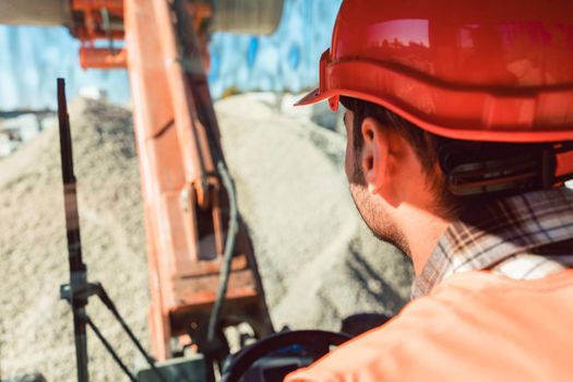 Worker on construction site operating wheel loader diligently