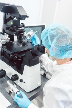 Woman doctor working in medical lab with manipulator and microscope