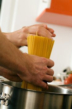 Couple - only hands to be seen - cooking pasta, putting the spaghetti in a pot with hot water
