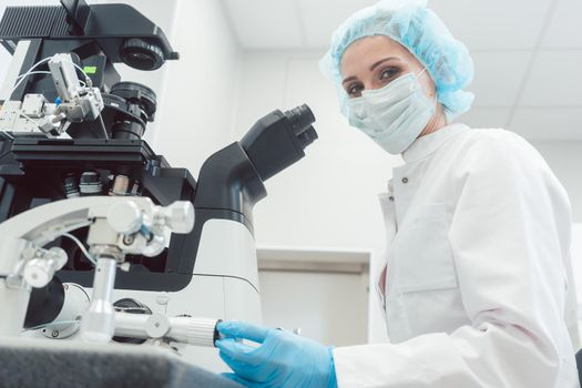 Woman doctor working in medical lab with manipulator and microscope