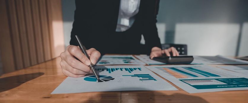 Close up Business woman using calculator and laptop for do math finance on wooden desk in office and business working background, tax, accounting, statistics and analytic research concept