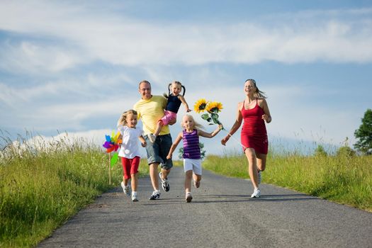 Family with three kids running down a hill