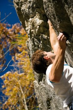 Man climbing a rock short before reaching the summit