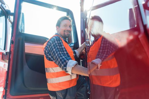 Truck driver in front of his long haul lorry getting in