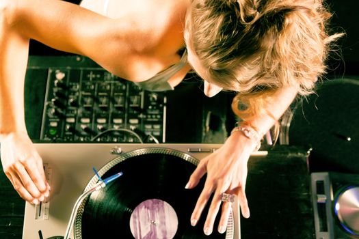 Female DJ at the turntable in a club, with mixer and old school record player