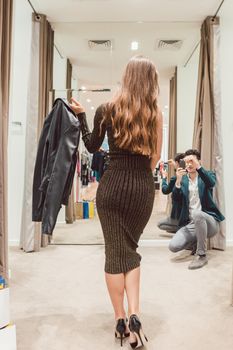 Man making phone photo of his wife with her new dress in fashion store