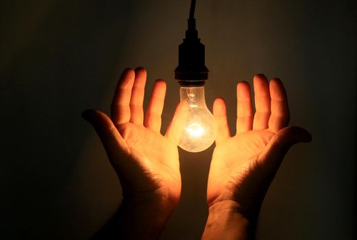 salvador, bahia / brazil - may 17, 2020: hands hold incandescent lamp lit in residence in the city of Salvador.