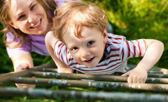 Little boy and his mother climbing up a ladder, they want to reach their tree house (house not to be seen)