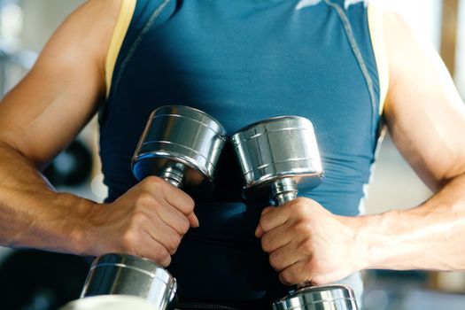 Strong man with dumbbells; focus on hand and dumbbell