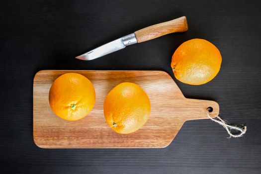 Oranges and old traditional pocket knife on a wooden cutting board