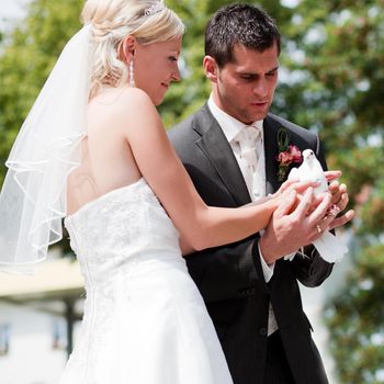 Happy wedding couple, they are holding doves in their hands and want to let them fly free as a symbol of love
