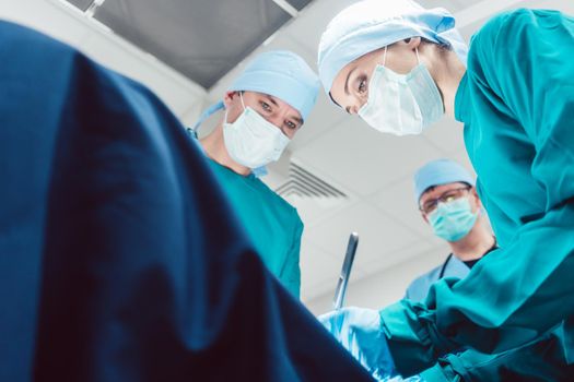 Team of surgeons in operation room during surgery from low angle view