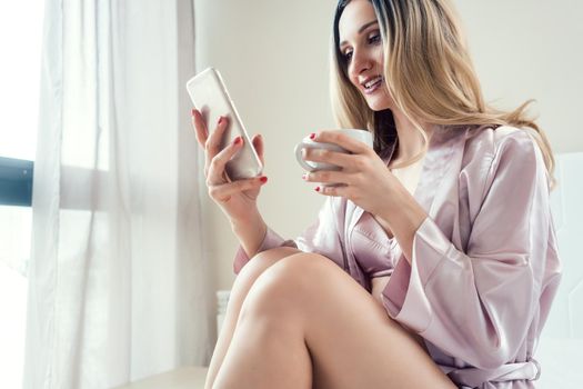 Woman checking her phone in the morning for messages on bed