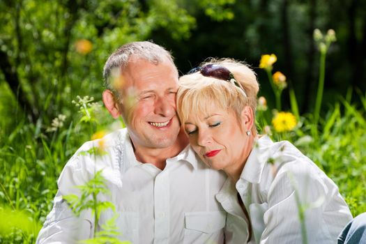 Mature couple sitting out in the green on a beautiful summer day