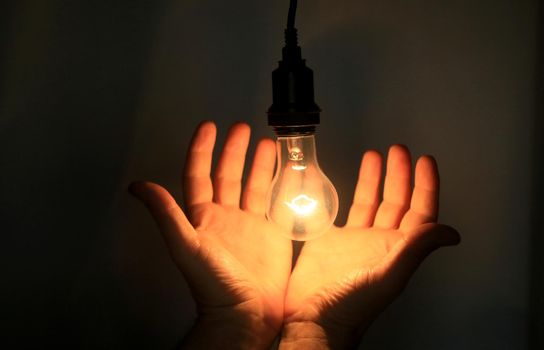 salvador, bahia / brazil - may 17, 2020: hands hold incandescent lamp lit in residence in the city of Salvador.