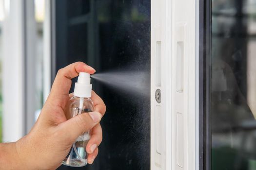 Cleaning door knob with alcohol spray for  Covid-19 (Coronavirus) prevention.