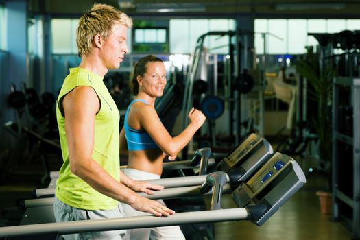 Couple in a gym working out on a treadmill