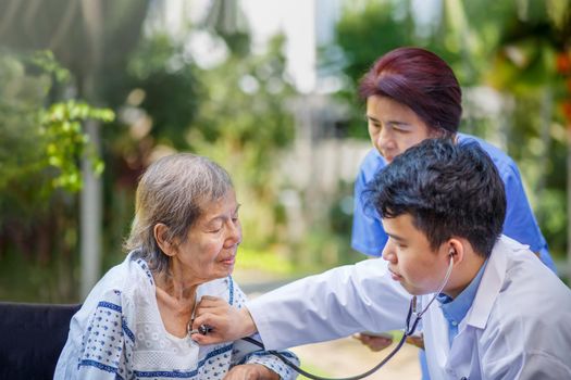 Doctor checking lung of elderly woman during homecare medical
