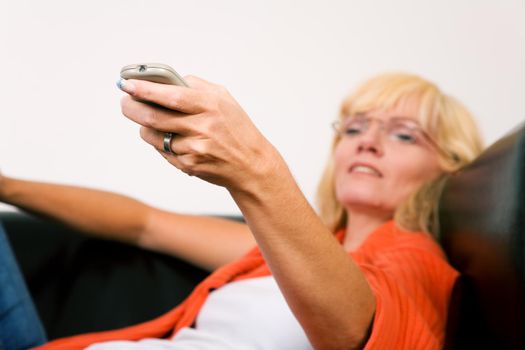Woman on a sofa with a tv remote control (focus on remote control)
