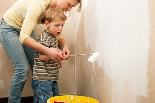 Family - mother with son - painting the wall of their new home or apartment, apparently they just moved in