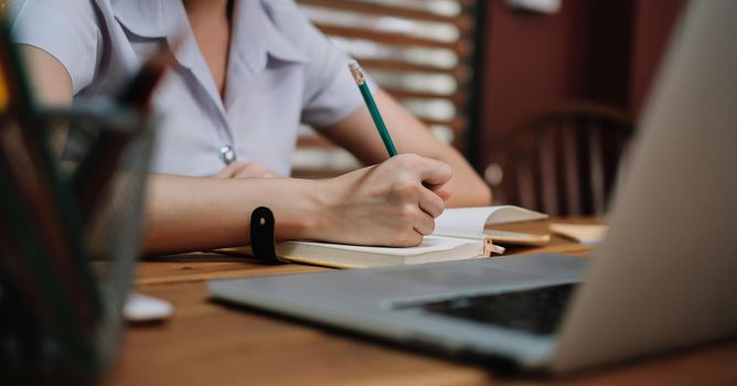 Close up student study online with teacher, young woman learn language listen lecture watch webinar write notes look at laptop sit in cafe, distant education