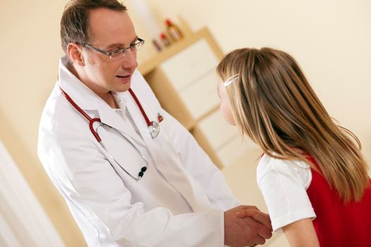 Doctor - Pediatrician - with a child patient in his practice, both are shaking hands