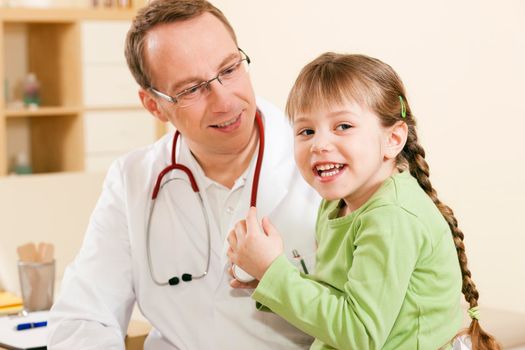 Doctor - Pediatrician - with a child patient in his practice, she is examining his stethoscope, friendly and light atmosphere