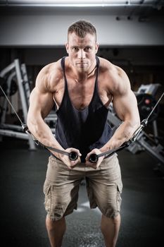 Bodybuilder doing butterfly on cable pull for better definition of his arm muscles