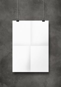 White folded poster hanging on a concrete wall with clips. Blank mockup template