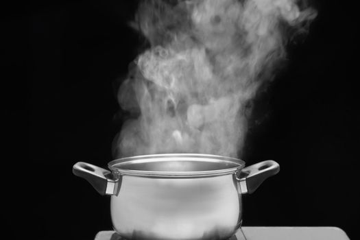 steam over cooking pot in kitchen on dark background