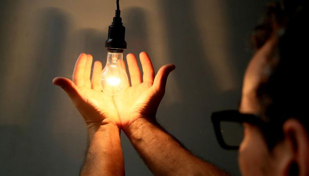 salvador, bahia / brazil - may 17, 2020: hands hold incandescent lamp lit in residence in the city of Salvador.