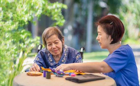 Elderly woman with caregiver in the needle crafts occupational therapy  for Alzheimer’s or dementia