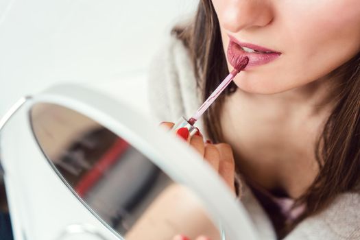 Beautiful woman applying makeup and lipstick