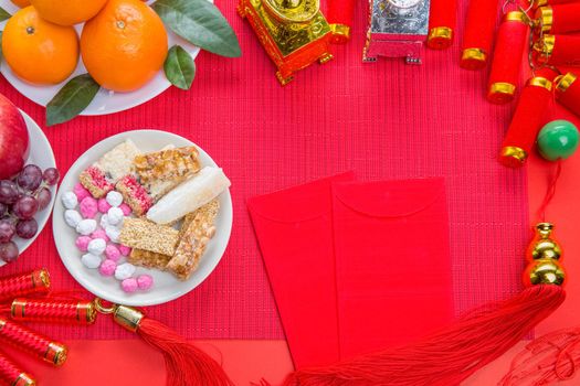 Flat lay Chinese new year festival decorations with orange apple grape and red packet. Texts appear in image meaning good fortune