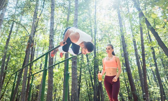 Sportive couple, woman and man, doing workout in outdoor gym