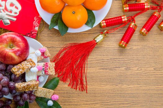 Flat lay Chinese new year festival decorations with orange apple grape and red packet. Texts appear in image meaning good fortune