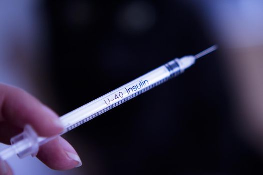 Insulin injecting syringe held by nurses hand. Copy space