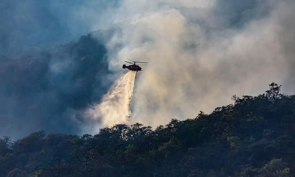 Helicopter dumping water on forest fire