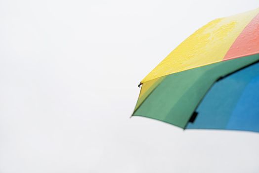 Rain drops on a colorful umbrella. Close up of colorful umbrella part with raindrops on sky background