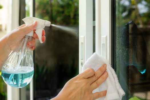 Woman is cleaning door handle with alcohol spray for  Covid-19 (Coronavirus) prevention.