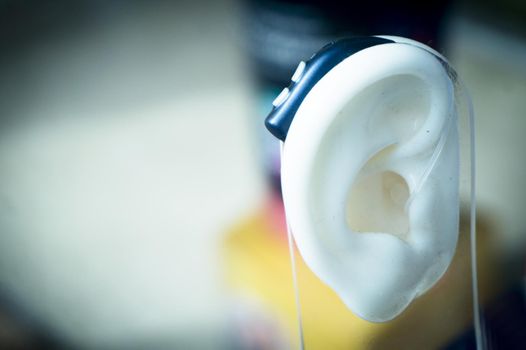 Plastic ear with modern hearing aid. No people