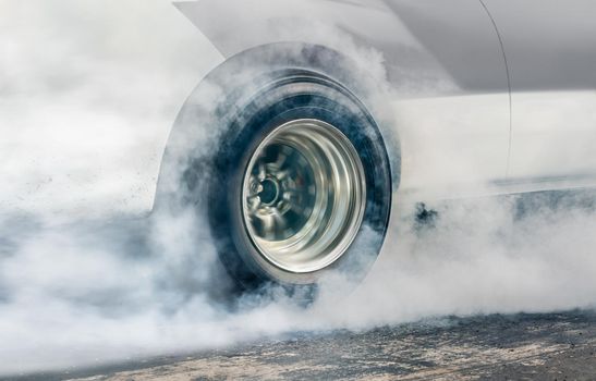 Drag racing car burns rubber off its tires in preparation for the race