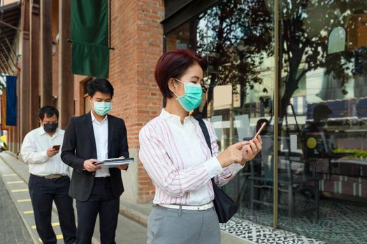 Asian middle aged people wearing mask and keep social distancing to avoid the spread of COVID-19