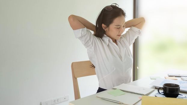 Businesswoman relaxing at comfortable in office hands behind head, happy woman resting in office satisfied after work.