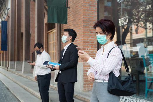 Asian middle aged people wearing mask and keep social distancing to avoid the spread of COVID-19