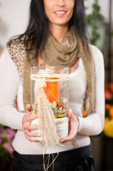 Female florist in flower shop or nursery with candle in glass