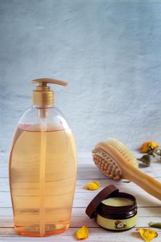 Shower gel in a large bottle, body massage brush and coconut oil for skin care.