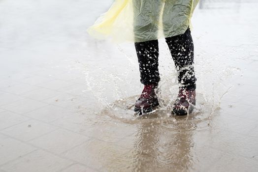 woman running on asphalt in rainy weather. Close up of legs and shoes splashing in puddles.